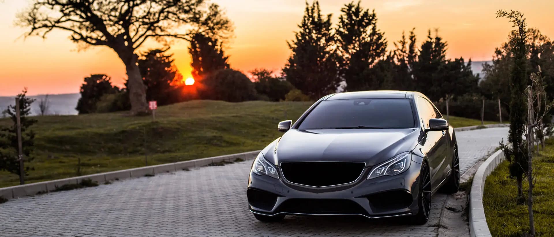 A silver Mercedes-Benz on a scenic drive at sunset